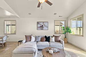 Living room with ceiling fan, light hardwood / wood-style floors, vaulted ceiling, and a textured ceiling