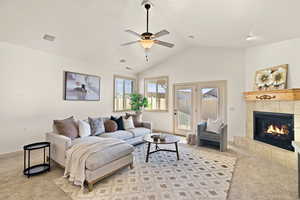 Living room with light carpet, a fireplace, lofted ceiling, and ceiling fan