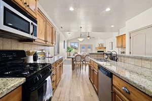 Kitchen with pendant lighting, lofted ceiling, sink, stainless steel appliances, and light hardwood / wood-style flooring