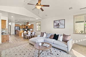 Living room with light hardwood / wood-style flooring, vaulted ceiling, and ceiling fan