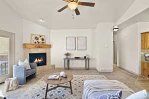 Living room with a tiled fireplace, lofted ceiling, and ceiling fan