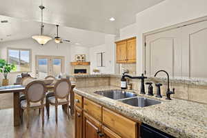 Kitchen featuring sink, a tile fireplace, backsplash, black dishwasher, and light wood-type flooring