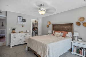 Carpeted bedroom featuring a spacious closet, a closet, and a textured ceiling