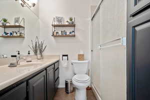 Bathroom with an enclosed shower, vanity, tile patterned floors, and toilet