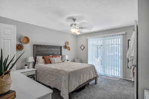 Carpeted bedroom with ceiling fan, access to exterior, and a textured ceiling