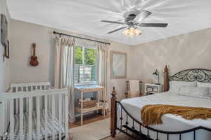 Bedroom featuring ceiling fan, wood-type flooring, and a textured ceiling