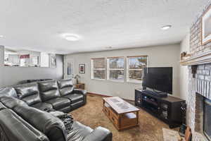 Carpeted living room with a fireplace and recessed lighting.