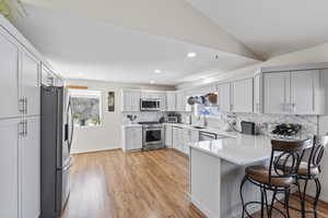 Remodeled kitchen, appliances with stainless steel finishes, vaulted ceiling, and a kitchen bar