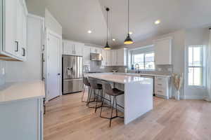 Kitchen featuring sink, stainless steel appliances, white cabinets, and a kitchen bar