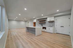 Kitchen featuring white cabinetry, sink, backsplash, and light hardwood / wood-style flooring