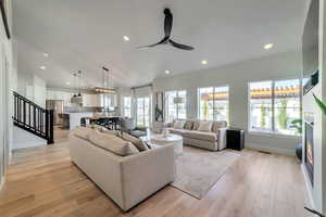 Living room with ceiling fan, lofted ceiling, and light wood-type flooring