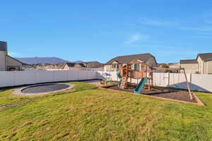 View of yard with a trampoline, a mountain view, and a playground