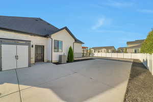 Rear view of house with central AC, a garage, and a patio area