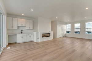 Unfurnished living room featuring sink and light hardwood / wood-style floors