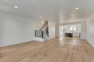 Unfurnished living room featuring light hardwood / wood-style floors and a chandelier