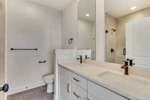 Bathroom with vanity, toilet, and a shower with shower door