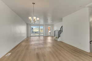 Unfurnished living room with an inviting chandelier and light hardwood / wood-style flooring