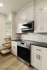 Kitchen featuring white cabinetry, appliances with stainless steel finishes, backsplash, and light hardwood / wood-style floors