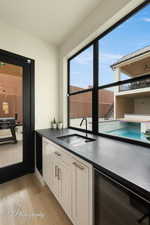 Kitchen with sink, white cabinets, beverage cooler, and light hardwood / wood-style flooring