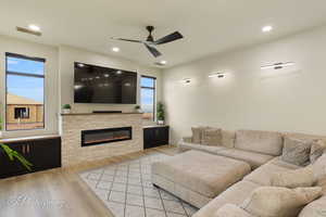 Living room with a fireplace, light hardwood / wood-style flooring, and ceiling fan