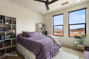 Bedroom with multiple windows, a mountain view, light hardwood / wood-style flooring, and ceiling fan