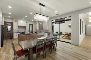 Dining space with sink, a chandelier, and light wood-type flooring