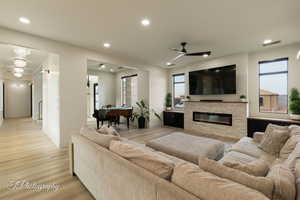 Living room featuring a stone fireplace, light hardwood / wood-style flooring, and ceiling fan