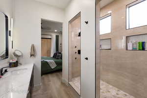 Bathroom featuring wood-type flooring, vanity, and a tile shower