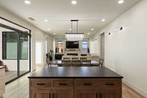 Kitchen with decorative backsplash, a center island, hanging light fixtures, and light wood-type flooring