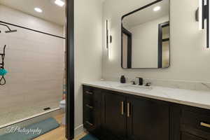 Bathroom featuring vanity, hardwood / wood-style floors, walk in shower, and toilet