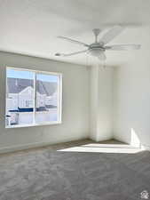 Carpeted spare room featuring ceiling fan and a textured ceiling