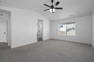 Carpeted empty room featuring lofted ceiling and ceiling fan