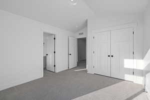 Bedroom featuring light carpet, vaulted ceiling, a closet, and ensuite bathroom