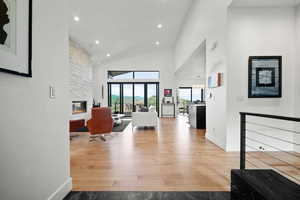 Interior space featuring a stone fireplace, light hardwood / wood-style flooring, and high vaulted ceiling