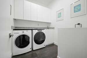 Washroom featuring cabinets, sink, and washing machine and clothes dryer