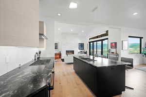 Kitchen featuring a breakfast bar, a fireplace, sink, light wood-type flooring, and a spacious island