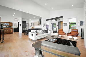 Living room featuring sink, high vaulted ceiling, and light wood-type flooring