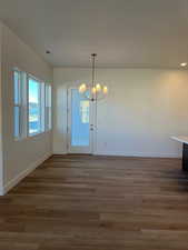 Unfurnished dining area featuring hardwood / wood-style flooring and a notable chandelier