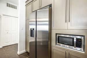 Kitchen with stainless steel appliances, dark tile patterned floors, and cream cabinets