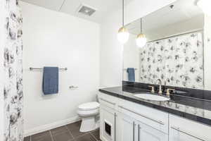 Bathroom featuring walk in shower, toilet, tile patterned floors, and vanity