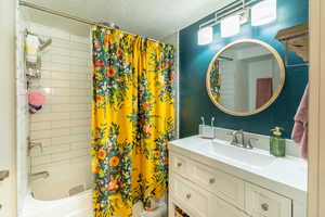 Bathroom with vanity, a textured ceiling, and shower / bath combo with shower curtain