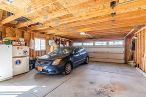 Garage with a garage door opener, a carport, and white refrigerator