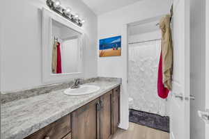 Bathroom with vanity, hardwood / wood-style flooring, curtained shower, and toilet