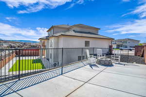 Rear view of property featuring a yard, a mountain view, a patio area, and a fire pit