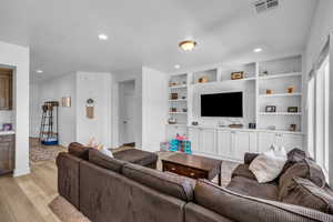 Living room featuring built in shelves and light wood-type flooring