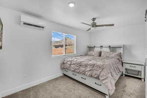 Bedroom featuring ceiling fan, light colored carpet, and a wall unit AC