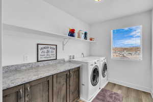 Washroom featuring cabinets, washer and dryer, and light hardwood / wood-style flooring