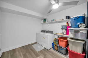 Laundry room with washing machine and dryer, ceiling fan, and light wood-type flooring