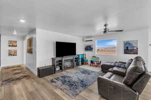 Living room featuring light wood-type flooring, a textured ceiling, and an AC wall unit