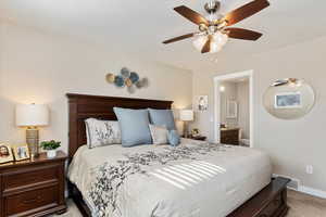 Carpeted bedroom featuring ceiling fan and ensuite bathroom